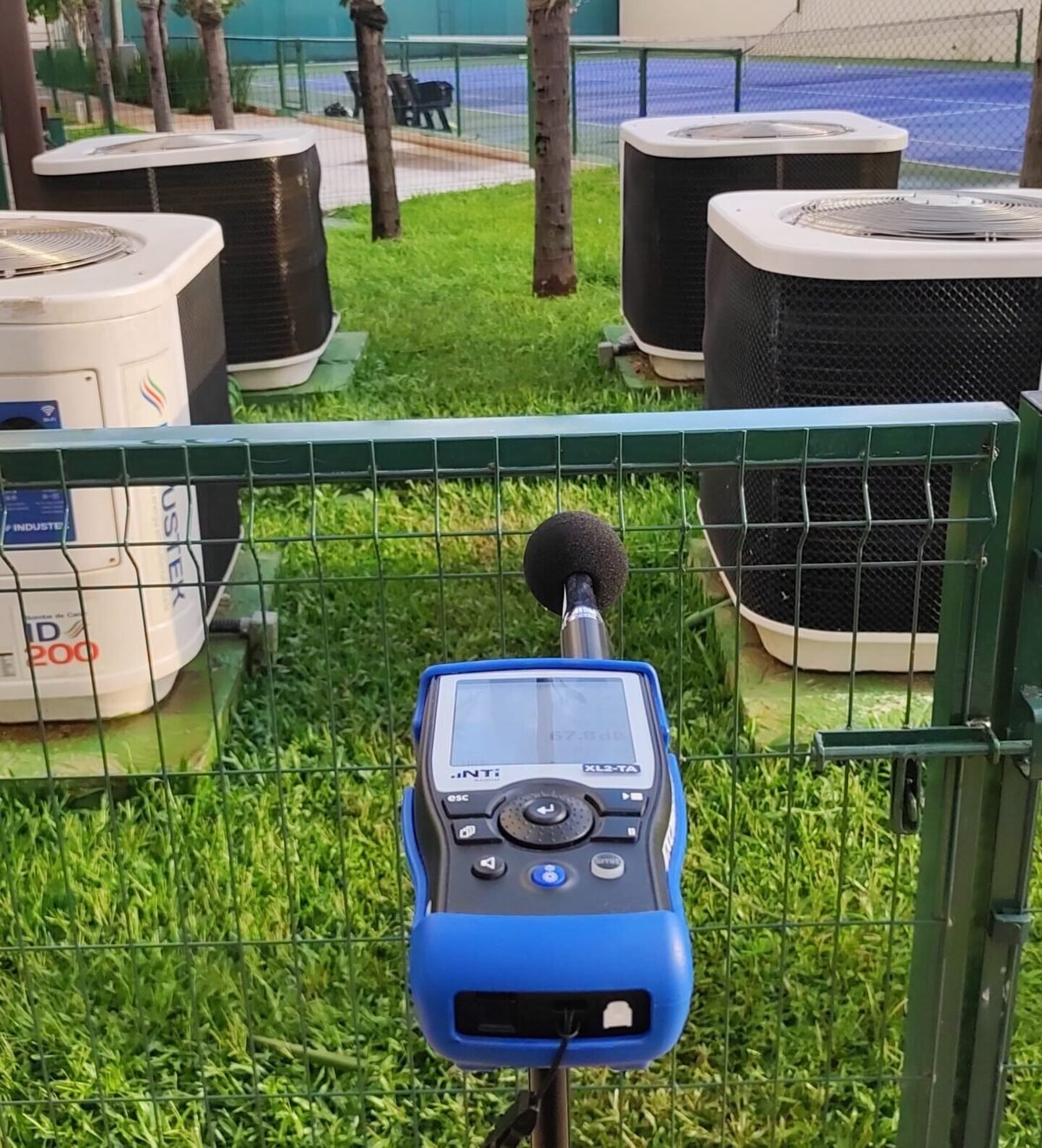 Medidor de nível sonoro posicionado junto a máquinas de ar-condicionado em condomínio residencial